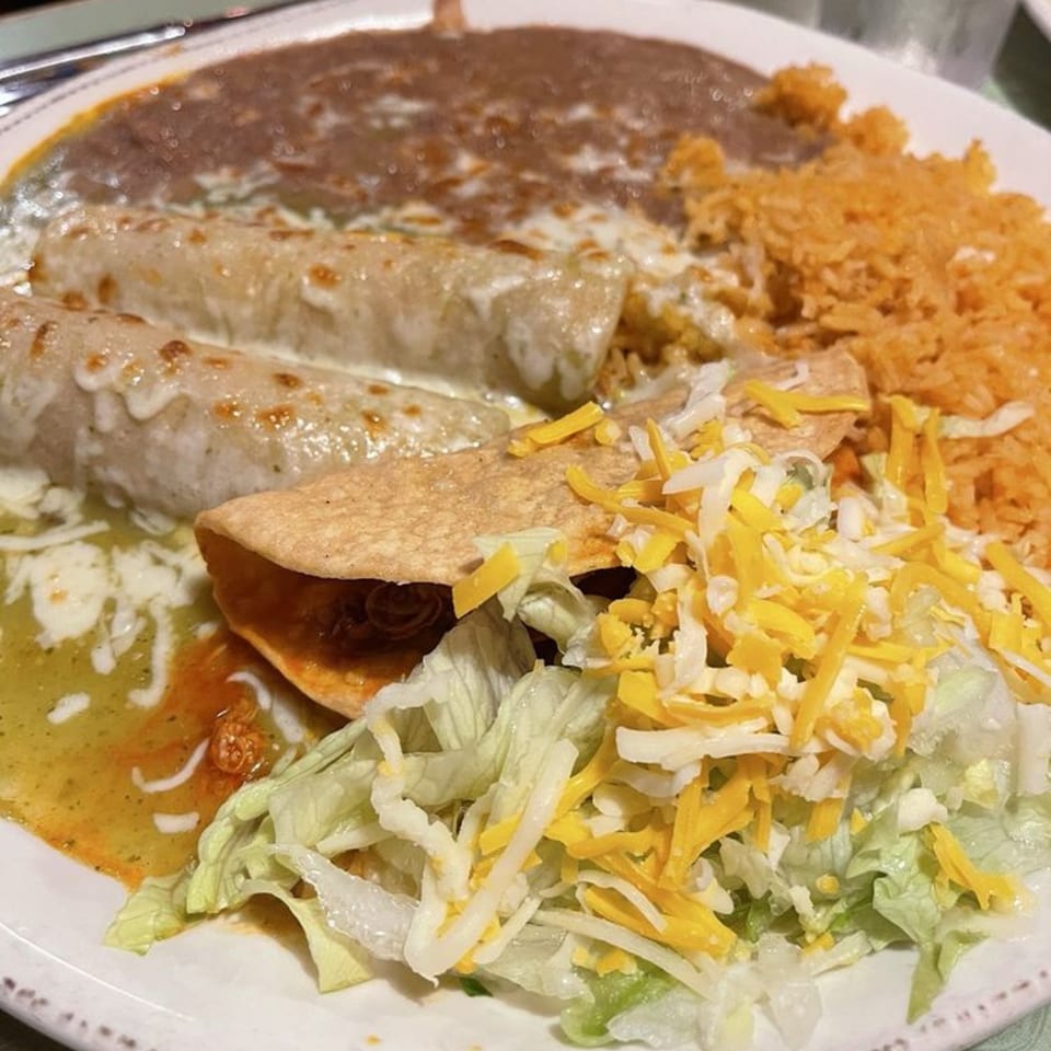 A Casa Mexico combo plate with enchiladas, refried beans, rice, and a taco with lettuce and cheese.