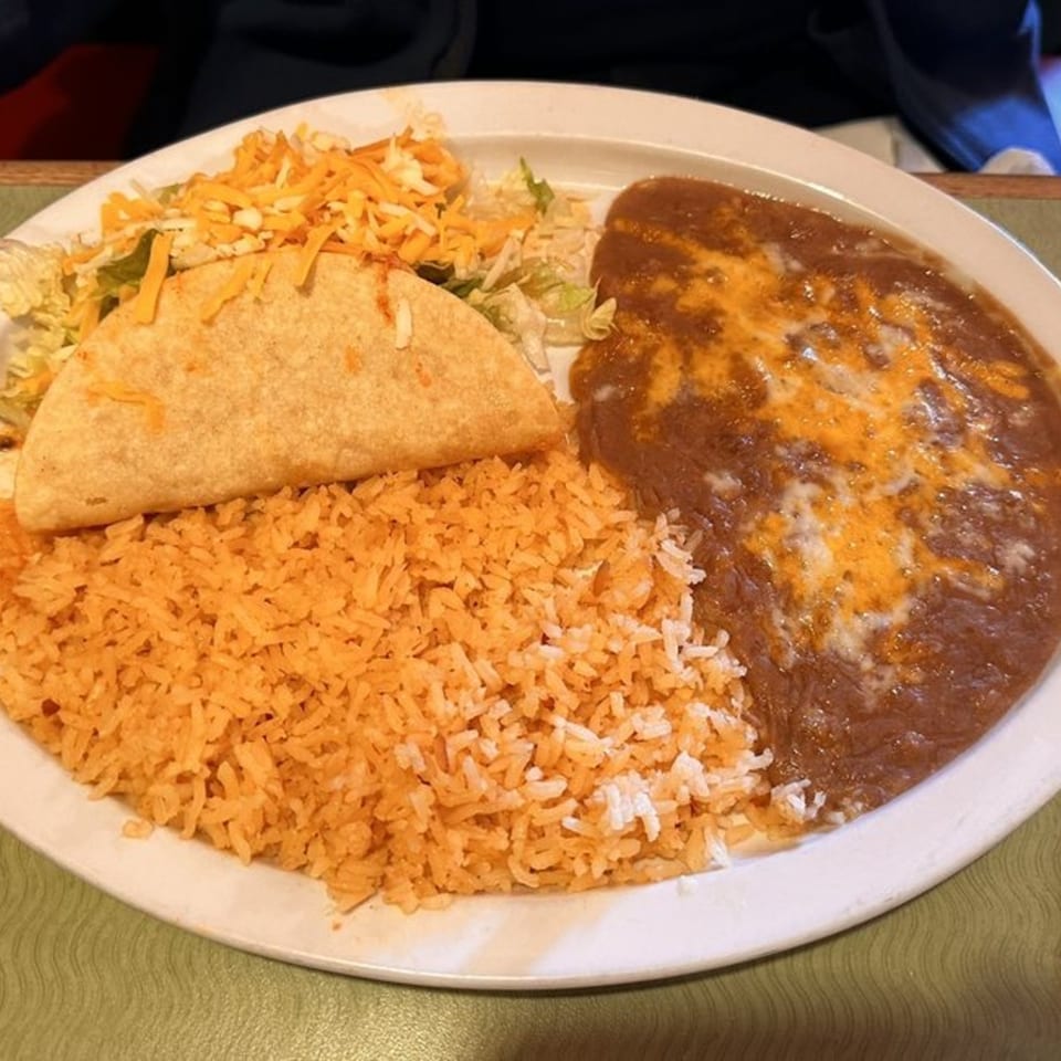A Casa Mexico plate with a taco, rice, refried beans with cheese, and a side salad.