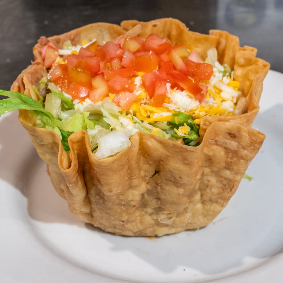 A Casa Mexico taco salad in a crispy tortilla bowl, topped with lettuce, cheese, and diced tomatoes.